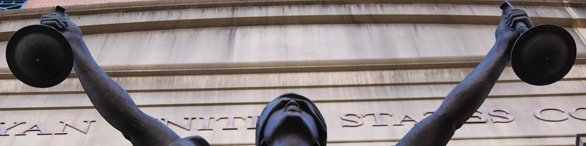 An image depicts a copper sculpture of Lady Justice, blindfolded and holding one scale in each hand outside of a courthouse.