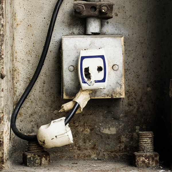 An image depicts a rusty, worn out, dysfunctional electrical outlet.