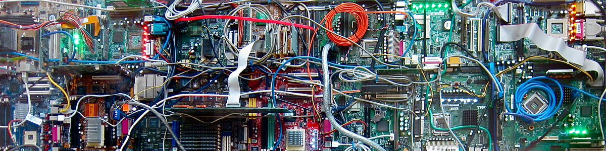 An close up image of a hard-drive; multiple wires--red, white, silver, off-white, blue, and teal--flow across the circuit board.